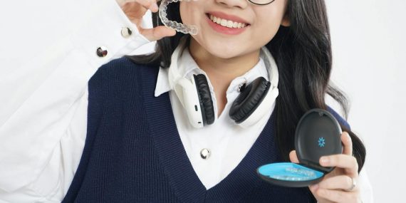 Teen holding clear aligners and an aligner case, demonstrating removable orthodontic trays used before eating and drinking